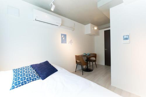 a bedroom with a white bed and a table at Bellie Sangenjaya by Tranova in Tokyo