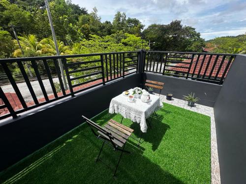 a table and chairs on a balcony with grass at The Deck Homestay & Event House in Jitra