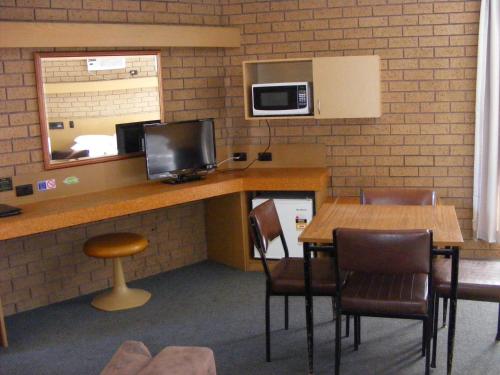 a room with a table with chairs and a microwave at Eaglehawk Motel Bendigo in Bendigo