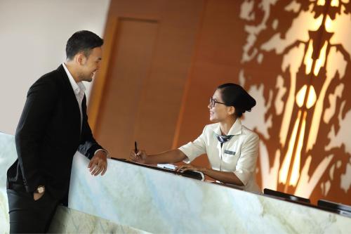 a man and a woman sitting at a desk at Resinda Hotel Karawang in Karawang