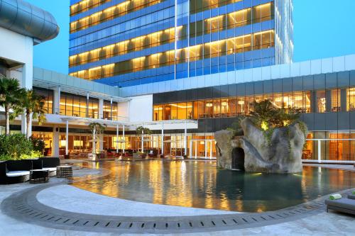 a building with a fountain in front of a building at Resinda Hotel Karawang in Karawang