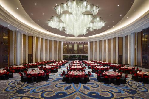 a large banquet hall with red tables and a chandelier at Resinda Hotel Karawang in Karawang