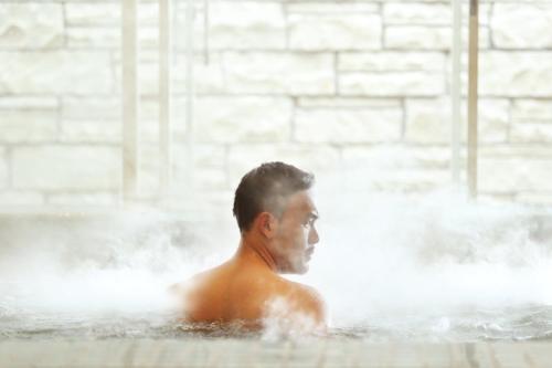 a man in a hot tub with water at Resinda Hotel Karawang in Karawang