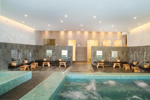 a bathroom with a swimming pool with tables and chairs at Resinda Hotel Karawang in Karawang
