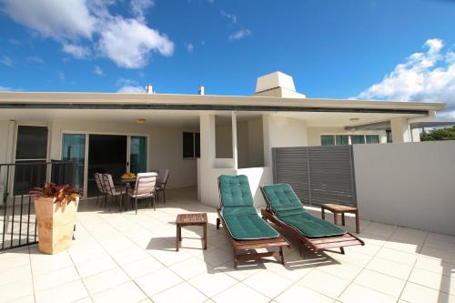 a patio with two chairs and a table on a house at Caloundra Central Apartment Hotel Official in Caloundra