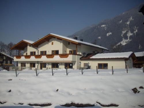 a large building in the snow with a mountain at Ferienhaus Zillertal in Stumm