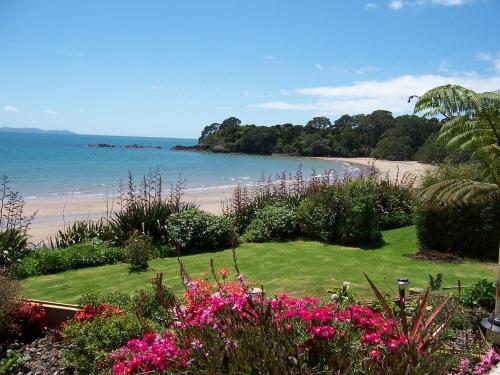 a view of a beach with pink flowers at By the Bay Beachfront Apartments in Mangonui