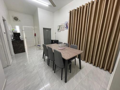 a dining room with a wooden table and chairs at Aufa Homestay 3 Bilik Aircond in Gua Sai