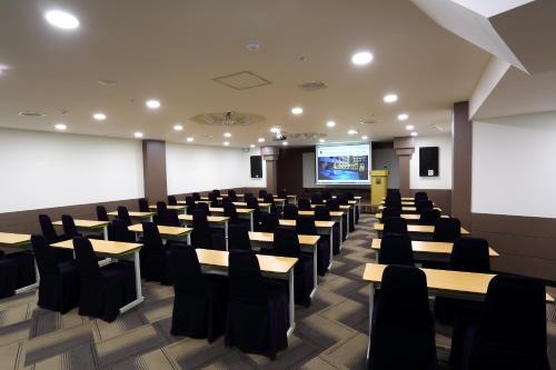 a conference room with tables and chairs and a screen at Benikea Swiss Rosen Hotel in Gyeongju