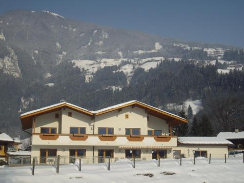a building in the snow with mountains in the background at Ferienhaus Zillertal in Stumm