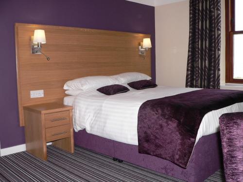 a bedroom with a large bed with a wooden headboard at Ayre Hotel & Ayre Apartments in Kirkwall