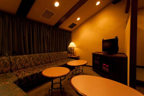 a living room with a couch and tables and a tv at Sun Members Hirugano in Gujo