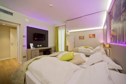 a hotel room with three beds and a tv at Aktivhotel Santalucia in Nago-Torbole