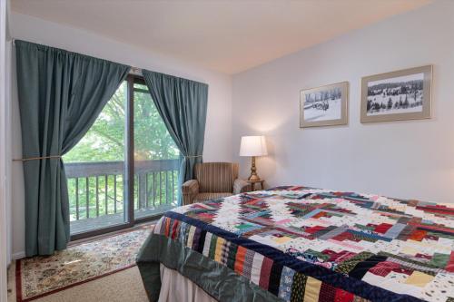 a bedroom with a quilt on a bed and a window at Sugarbush Summit Condo in Warren