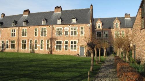een groot bakstenen gebouw met bomen ervoor bij Hotel Guesthouse Begijnhof in Leuven