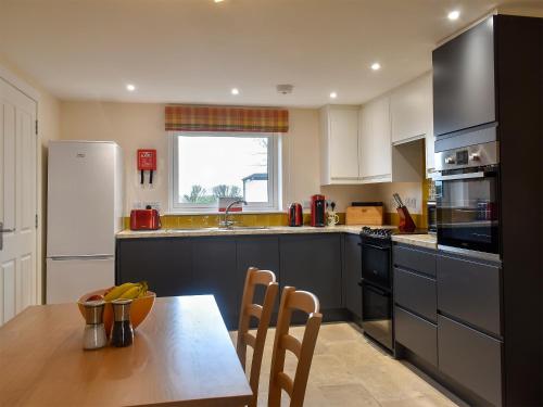 a kitchen with a wooden table and a dining room at The Annex At Fernyrig in Birgham