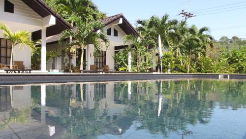a swimming pool in front of a house with palm trees at Privacy Resort - Koh Chang in Ko Chang