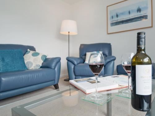 a bottle of wine and two glasses on a table in a living room at Little Orchard in Farmborough