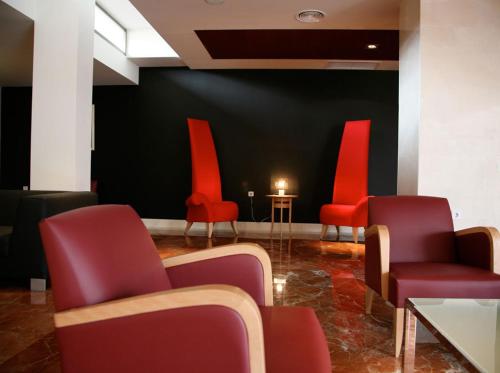 a waiting room with red chairs and a table with a candle at TCH Hotel in Lorquí