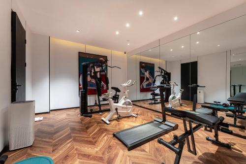 a gym with treadmills and exercise bikes and mirrors at HeSu Hidden Art Hotel & Suites - Near Bell Tower & Ideal Location-Spacious rooms featuring King or Double Queen beds -Exclusive Two&Three-Bedroom Suites with Expansive Living Rooms for Group Gathering-Kitty Cuddles & Coffee Gift -Seamless Journey Planning in Xi'an