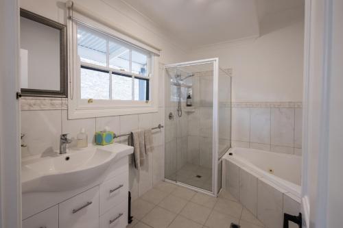ein weißes Badezimmer mit Waschbecken und Dusche in der Unterkunft St Helen's Cottages in Clare