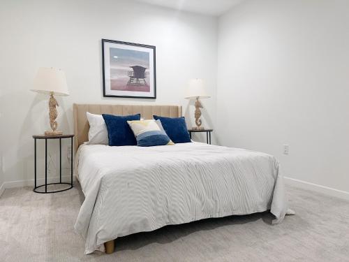 a white bedroom with a large bed with blue pillows at Wake Up on the Waters Edge in Los Angeles