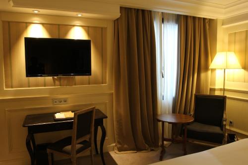 a hotel room with a desk and a television on a wall at Katriya Hotel and Tower in Hyderabad