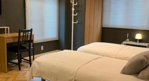 a bedroom with two beds and a desk and a chair at HOSTEL LUND I -Oimachi- in Tokyo