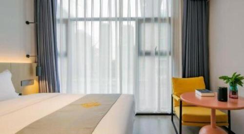 a bedroom with a bed and a table and a window at Airfeel Hotel in Ziyang