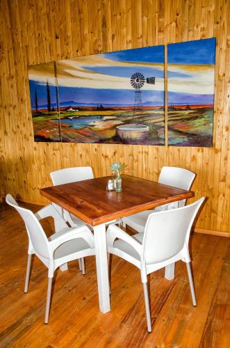 a wooden table with white chairs and a painting on the wall at Sevens Guesthouse in Kroonstad