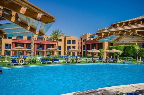 uma piscina num resort com cadeiras e guarda-sóis em Titanic Beach - Families and Couples only em Hurghada