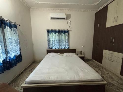a bedroom with a large bed with blue curtains at Parmarth Lok in Deoghar