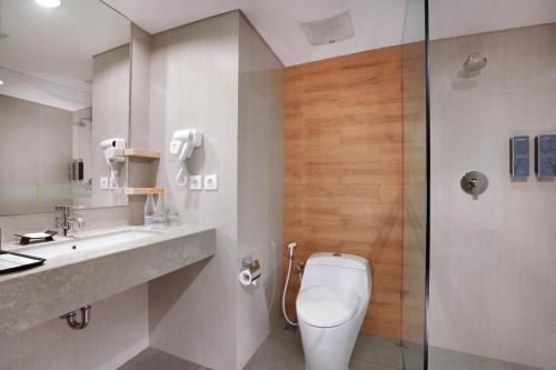 a bathroom with a toilet and a sink and a shower at Harper MT Haryono by ASTON in Jakarta