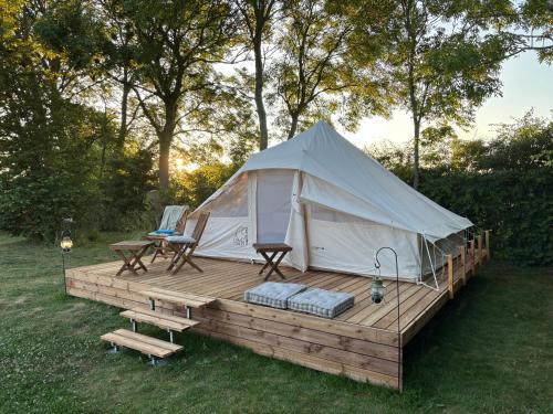 Tenda su una terrazza in legno con tavolo e sedie di Myregaard B & B and Apartments a Snogebæk