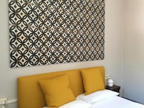 a painting above a bed with a yellow couch at Bed & Breakfast Dèco in Torno