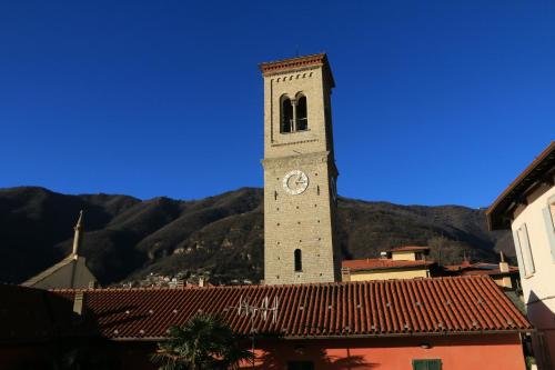 a clock tower in a town with mountains in the background at Bed & Breakfast Dèco in Torno
