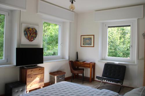 a bedroom with a bed and a desk and two windows at Dolomiti house in Cibiana
