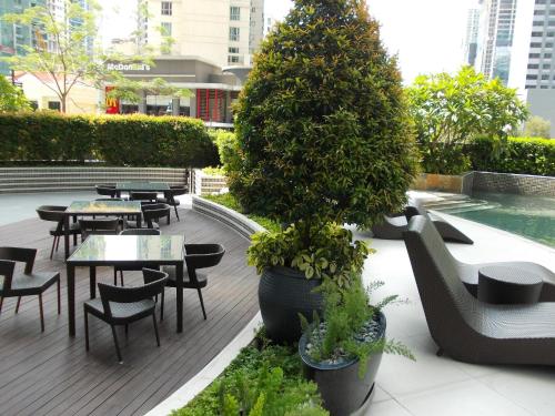 a patio with tables and chairs and a tree at Avant Serviced Suites - Personal Concierge in Manila