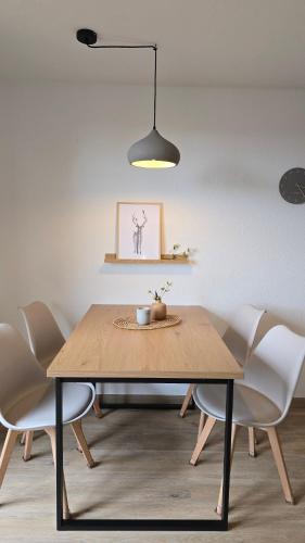 a dining room with a wooden table and white chairs at Waldliebe in Bad Sachsa