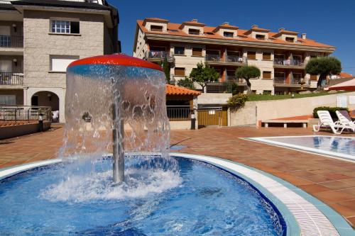 a fountain in the middle of a swimming pool at Apartamentos Esperanza del Mar in Portonovo