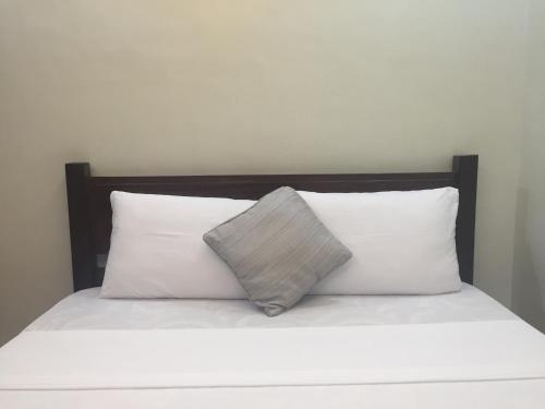 a bed with white pillows and a wooden headboard at Seaslugs Travellers Inn in El Nido
