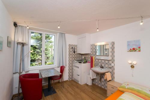 1 dormitorio con cama, escritorio y lavamanos en Chesa Quadrella jedes Zimmer mit Küchenzeile inklusive Bergbahnen im Sommer en Pontresina