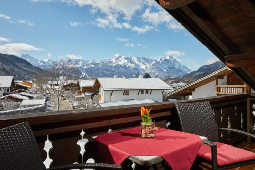 Una mesa con un jarrón de flores en un balcón. en Hotel Garni Zugspitz, en Farchant