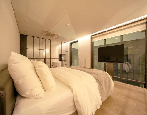 a bedroom with a white bed with a flat screen tv at JS Boutique Hotel in Hwaseong