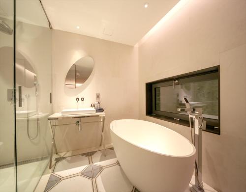 a bathroom with a white tub and a sink at JS Boutique Hotel in Hwaseong
