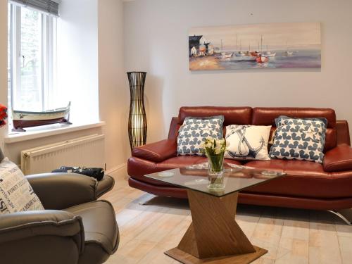 a living room with a brown leather couch and a table at Roland Cottage in Falmouth