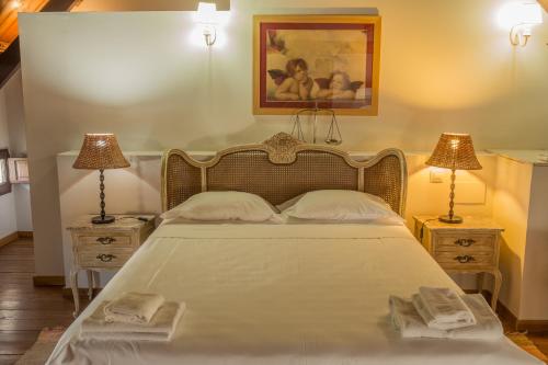 a bedroom with a large white bed with two lamps at Reservaloen Hacienda las Marciagas in Benacazón
