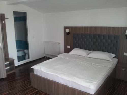 a bedroom with a large bed with a gray headboard at Hotel La John in Vama Veche