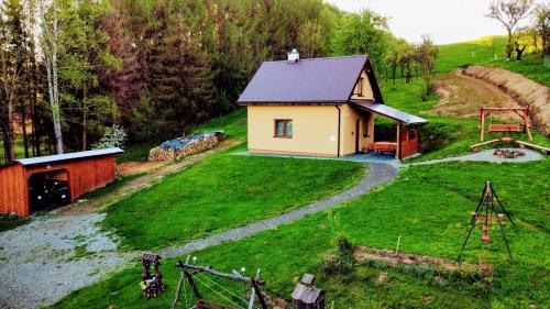 a small house in the middle of a green field at Domek na Wzgórzu in Zahoczewie