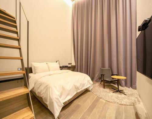 a bedroom with a bed and a ladder and a chair at JS Boutique Hotel in Hwaseong